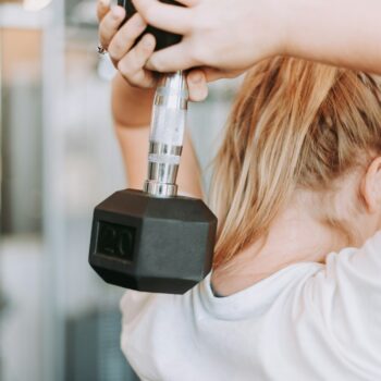 woman holding dumbbell in white crew-neck t-shirt