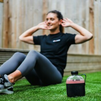 woman in black crew neck t-shirt and black leggings lying on green grass field