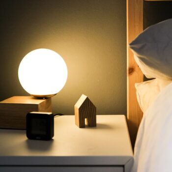 A warm, low-light lamp glowing beside a cosy bed—perfect for a calming wind-down routine to lower cortisol levels naturally and improve sleep.