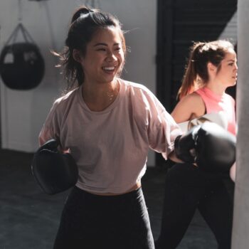 woman in pink long sleeve shirt and black pants holding black kettle bell