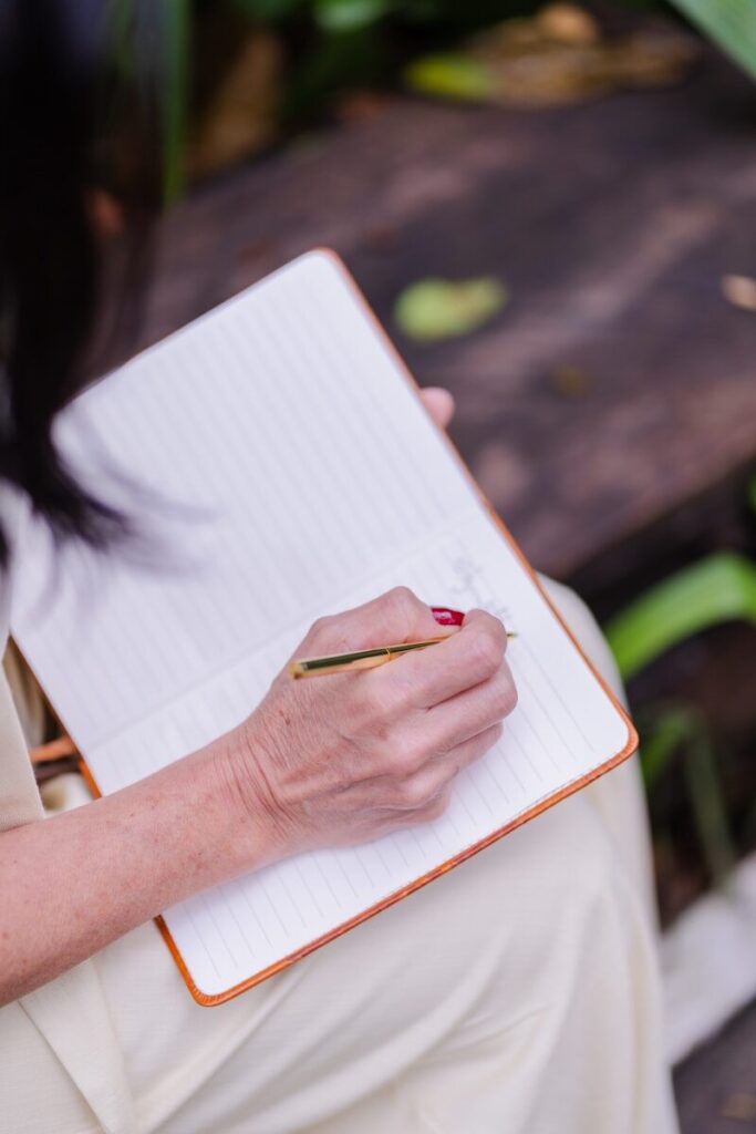A person writing in a lined notebook with a pen.